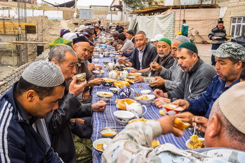 Foto: Geselliges Mittagessen von Männern an einer langen Tafel. 