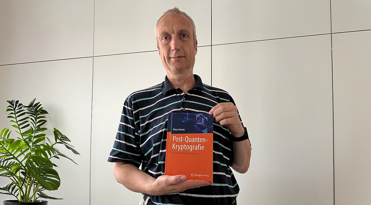Klaus Schmeh mit Buch im Büro