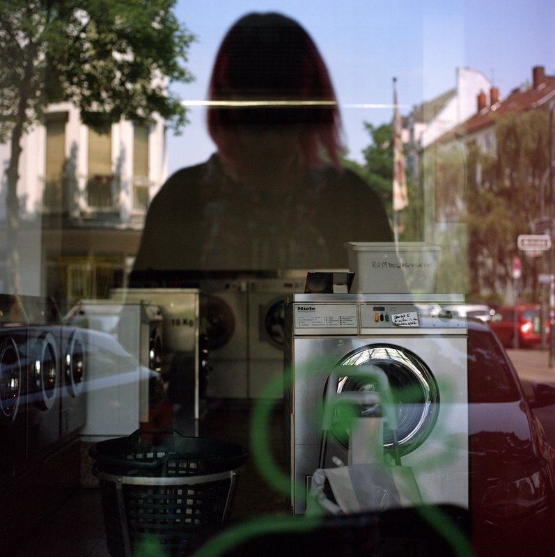 Foto: Spiegelung einer Person in der Fensterscheibe eines Waschsalons.